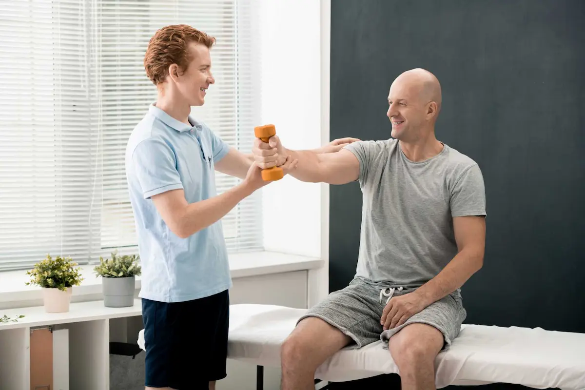 Ortho Services - young smiling physiotherapist helping mature male